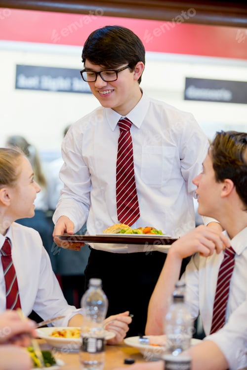 Preview: Vertical Shot Of A Male High School Student Standing Next To His Friends Eating Lunch In The School