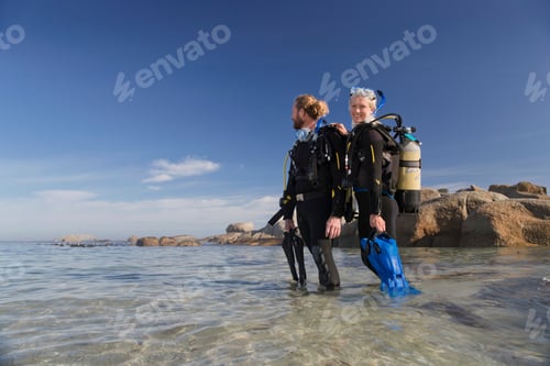 Preview: Couple In Wetsuits Going Ocean Scuba Diving From Beach