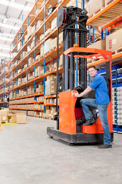 Preview: Vertical Wide Shot Of A Worker Smiling At The Camera While Standing Against A Forklift At The