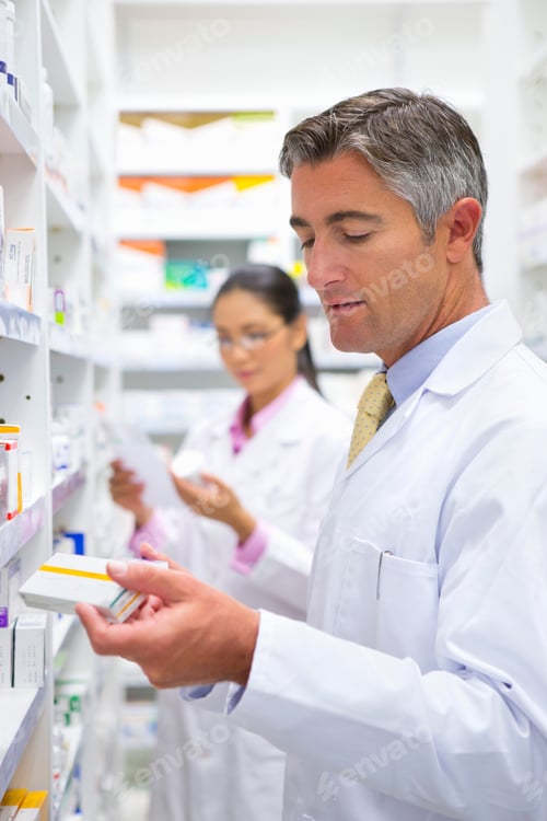 Preview: Vertical Shot Of A Male Pharmacist Reading The Label On A Medicine Boxes At A Pharmacy With A