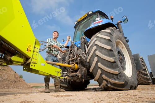 Preview: Wide Shot Of A Farmer Attaching Farming Equipment To The Tractor