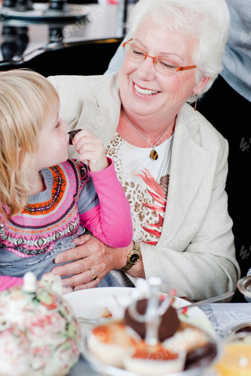 Preview: A Little Girl Sitting On Her Grandmothers Knee Eating Cake