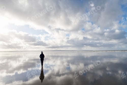 Preview: Silhouetted Reflection Of A Woman Standing On The Wet Portion Of The Beach During Low Tide