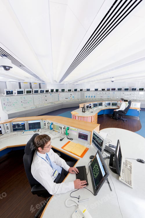 Preview: High-Angle Vertical Shot Of Two Engineers At Their Control Desks Using Computers In The Control