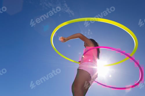 Preview: Low Angle Shot Of A Girl Hula Hooping With Two Plastic Hoops
