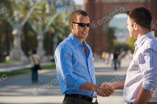 Visualização: Dois empresários apertando as mãos e sorrindo ao ar livre na Espanha, Barcelona.
