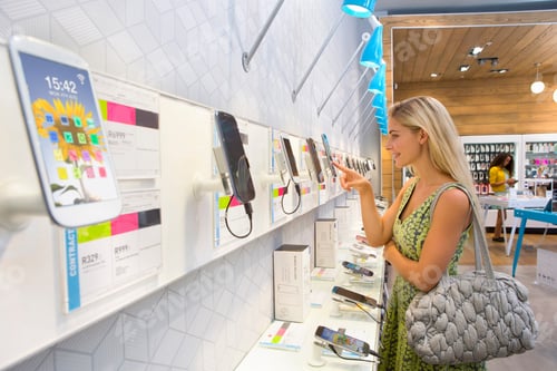 Preview: Young Woman Browsing Through Smart Phones In A Phone Store