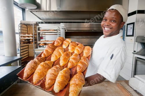 Preview: Smiling Baker Holding A Tray Of Bread In A Bakery Kitchen