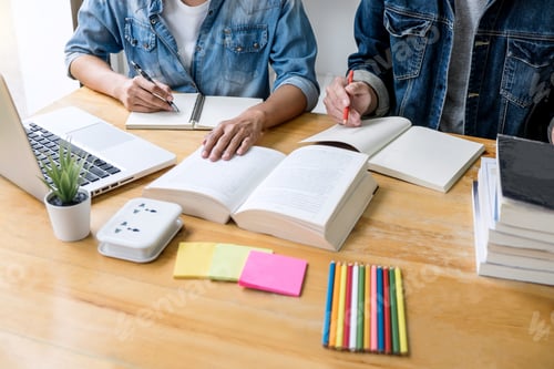 Preview: High School Tutor Or College Student Group Sitting At Desk In Library Studying And Reading, Doing