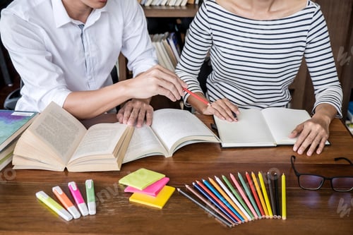 Preview: High School Or College Student Group Sitting At Desk In Library Studying And Reading, Doing