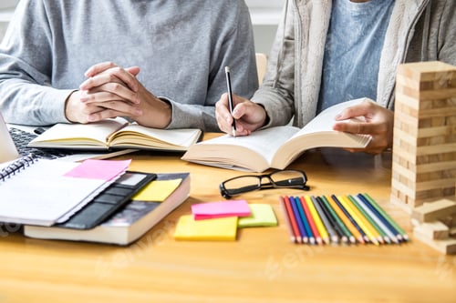 Preview: High School Tutor Or College Student Group Sitting At Desk In Library Studying And Reading, Doing