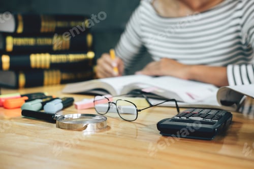 Preview: Woman Studying at Desk with Books and Calculator