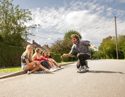 Preview: Four Young Women Sitting On Kerb Watching Skateboarder
