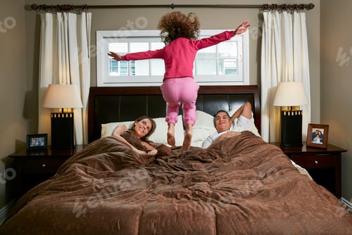 Preview: Rear View Of Girl In Mid Air Jumping On Parents Bed