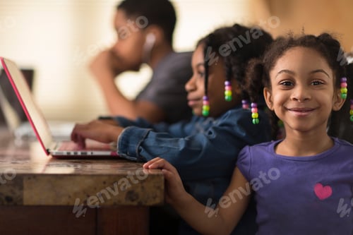 Preview: Portrait Of Girl At Dining Table And Siblings Using Laptops