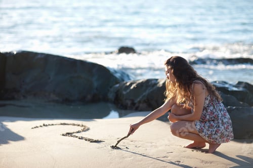 Preview: Woman Drawing Question Mark In Sand