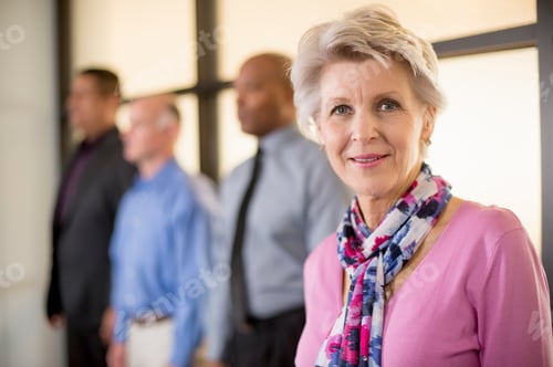 Preview: Elegant Senior Woman with Colleagues in Background