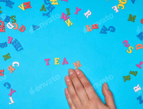 Preview: Female Hand And Multicolored Wooden Letters Of The English Alphabet On A Blue Background
