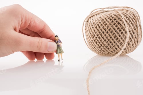 Preview: Woman Figure Beside A Linen Spool Of Thread On A White Background
