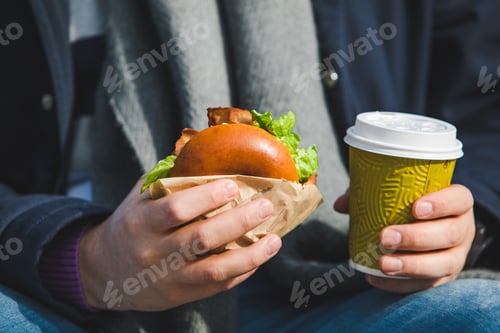 Preview: Man Hands Close Up Holding Burger With Coffee Cup. Outdoors