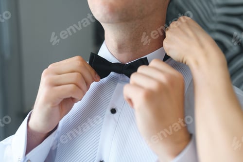 Preview: Man Adorned in Elegant Shirt, Getting Bowtie Tied