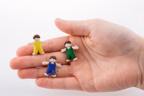 Preview: Hand Holding Colorful Dressed Children Figures On A White Background
