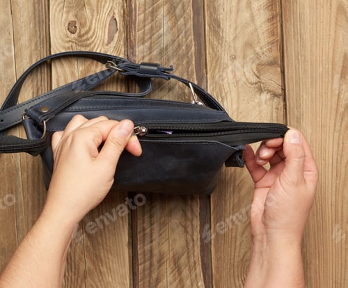 Preview: Two Female Hands Hold A Blue Leather Bag On A Gray Wooden Background, Top View