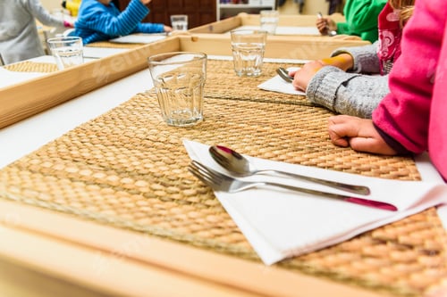 Preview: Children Sitting At The Table In A School Cafeteria While The Teachers Serve Them Food.