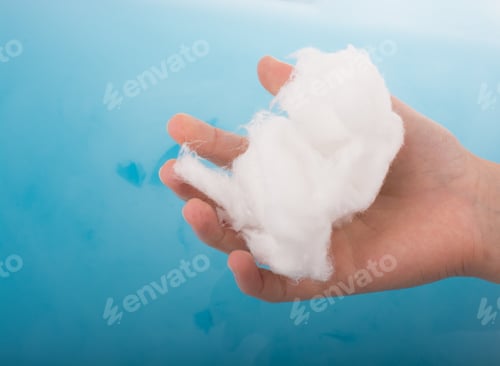 Preview: Hand Holding Some Cotton In Hand Over Blue Water
