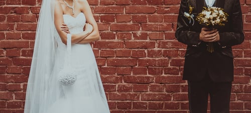 Groom And Bride Embracing Next To Red Brick Wall. Hands Of Newlyweds Together. Wedding Couple.