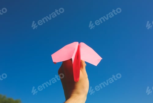 Preview: Guy Is Holding A Pink Handmade Plane. Freedom Concept Photo With A Blue Sky On Background. Travel