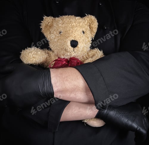 Preview: Man In Black Clothes Holding A Brown Teddy Bear In His Hands, Black Background