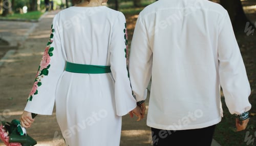 Preview: Wedding Couple In Traditional Suits Is Walking Outdoors In The Park. Groom In Embroidered Shirt And
