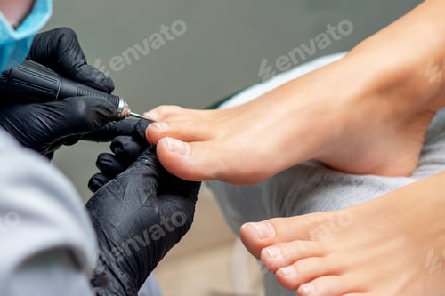Preview: Pedicurist'S Hands In Gloves With Special Tool Doing Pedicure Of Female Nails On Feet. Foot