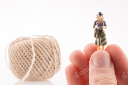 Preview: Woman Figure Beside A Linen Spool Of Thread On A White Background