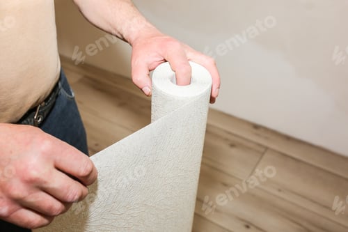 Preview: Man Is Holding Roll Wallpaper In Hands. Maintenance Repair Works Renovation In The Flat
