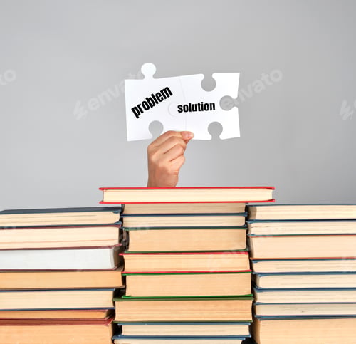 Preview: Female Hands Holding Big White Puzzles Over A Stack Of Books, Gray Background, Problem Solving