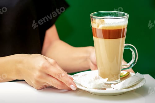 Preview: Close Up Of Female Waiter Gives Cup Of Coffee Latte With Candy In Plate On The Table
