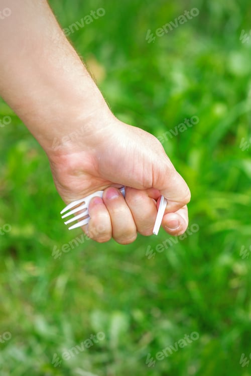 Preview: Hand Of A Little Girl Holding Plastic Trash On A Background Of Green Grass In The Park