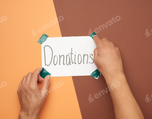 Preview: Two Male Hands Hold A Sheet Of Paper With The Inscription Donations, Brown Background