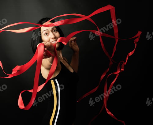 Preview: Young Woman Gymnast Of Caucasian Appearance With Black Hair Spins Red Satin Ribbons, Gymnastic