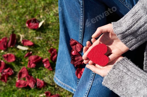 Red Heart Held in Hands on Green Grass