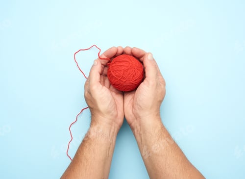 Preview: Two Male Hands Hold A Ball Of Red Woolen Threads, Blue Background, Top View