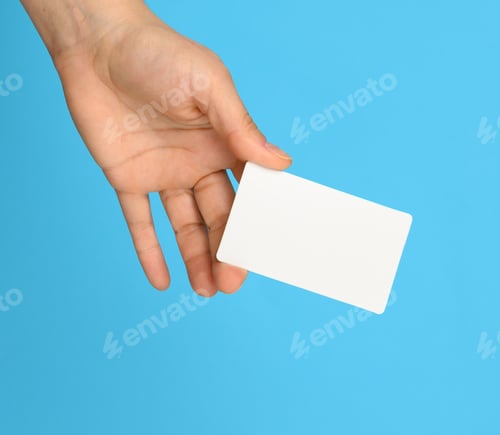 Preview: Female Hand Holding A White Business Card, Blue Background, Close Up