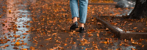 Preview: Woman Walking By Wet Streets After Rain. Yellow Leaves On Ground. Autumn Is Coming