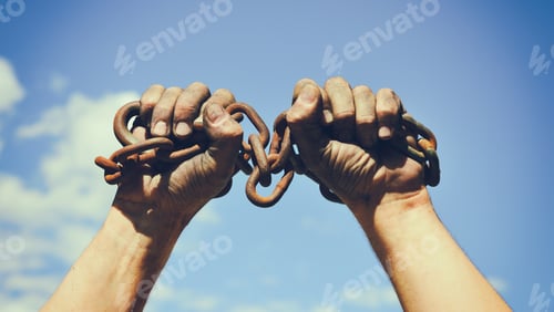 Preview: Two Dirty Male Hands Wrapped In A Rusty Iron Chain Raised Up Against A Blue Sky