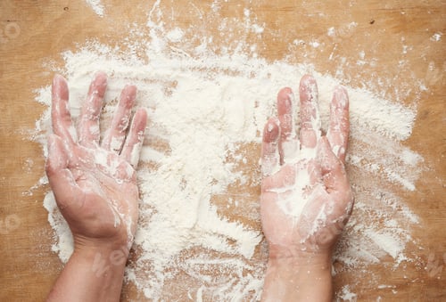 Preview: Two Hands And White Wheat Flour Scattered On A Brown Wooden Background, Product Is Spread Over The