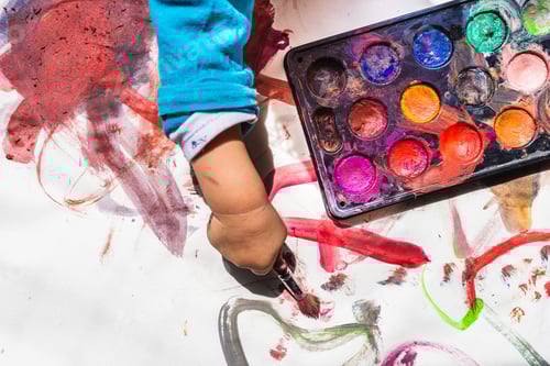 Preview: Toddler's Hand with Paintbrush and Colorful Watercolor Palette