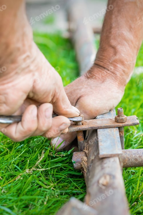 Preview: Hand Of An Elderly Man Twisting The Nut With A Wrench Outdoors. Repair By Wrench.