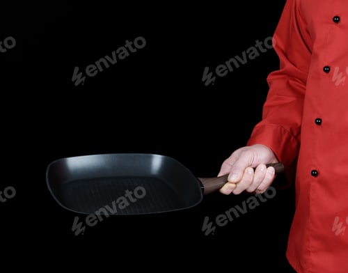 Preview: Cook In Red Uniform Holding An Empty Square Black Frying Pan, Black Background